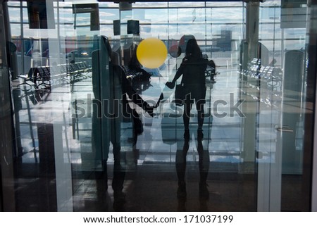 Reflection in window of friends holding hands. They are ready to start a trip by plane