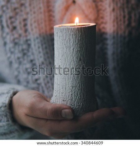 Handmade candlestick is holding by hands. Winter sweater is a background Holiday and Christmas atmosphere.
