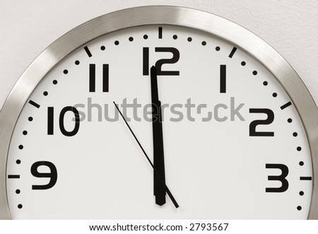 A modern wall clock showing five seconds until midnight. Time is running out.