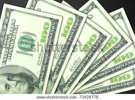 Several one hundred dollar bills fanned out on a plain dark gray background