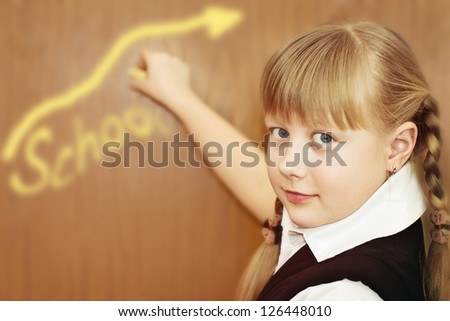 Little schoolgirl is writing on a blackboard