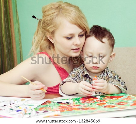 Mother teaching her little son to draw