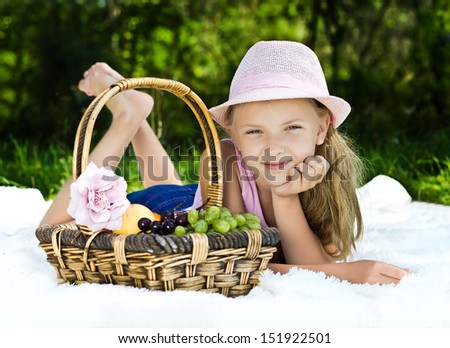 Portrait of girl with basket of fruit on green meadow