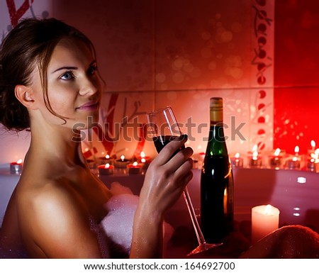Young Woman In A Jacuzzi With A Glass Of Wine And Candles