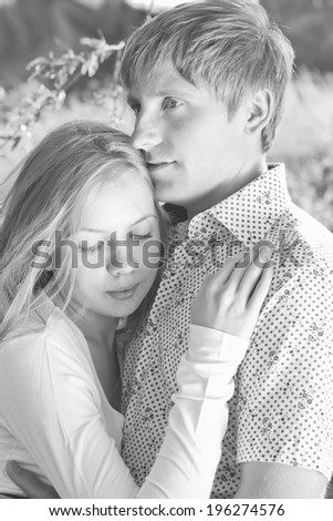 Black and white photo of couple in love tenderly embraces outdoors