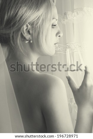 Closeup profile of sad bride with wine glass at window