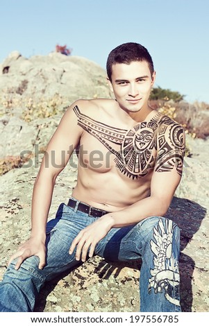 Portrait of sexy man with ethno tattoo outdoors