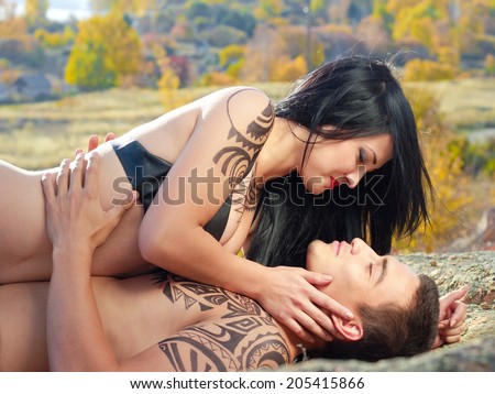 Young kissing passion couple with ethno tattoo