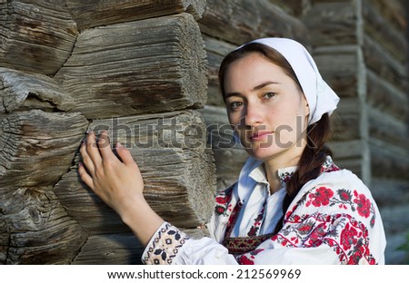 Russian girl in ethnic costume at russian log hut