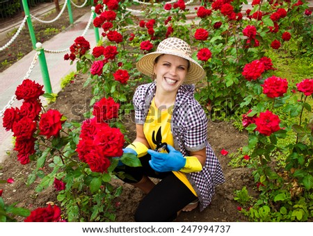 Young laughing woman gardening with roses in garden