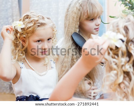 Two girls making hair dress at mirror before party
