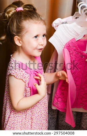 Adorable smiling girl choosing dress