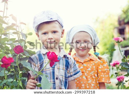Russian boy and girl at roses in garden