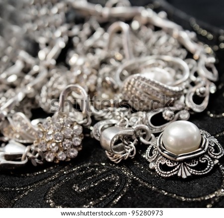 Various silver shining jewellery and closeup pearl on black