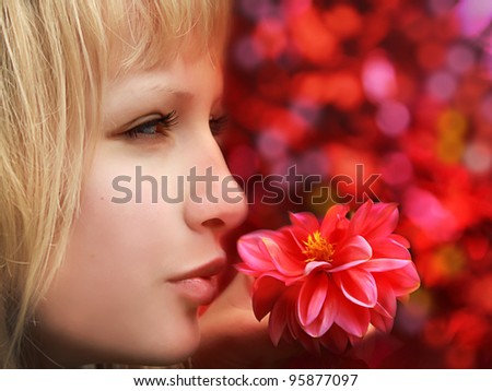 Closeup profile of beautiful blond woman with flower on red background