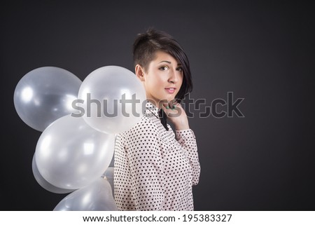 Teenage girl holding lots of white balloons, over white background.