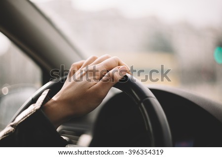 Close-up of a woman\'s hand driving a car