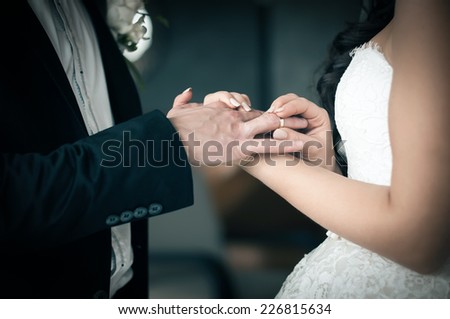 Bride puts on a wedding ring on groom\'s finger