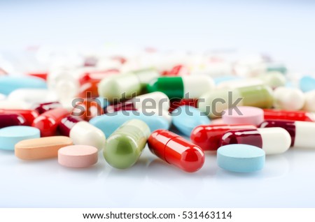 Pharmacy theme. Multicolored Isolated Pills and Capsules on the White Surface. Closeup.