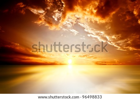 Red sunset over the sea, rich in dark clouds, rays of light