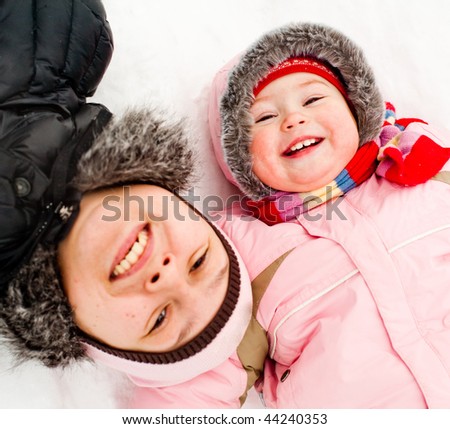Mom and daughter lying on a snow, smiling