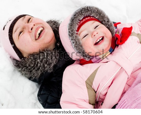 Mom and daughter lying on a snow, laughing