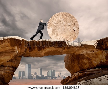 businessman pushing a stone wheel