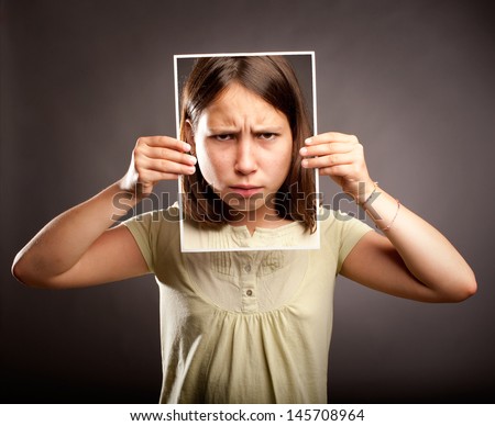 portrait of young girl holding a photography of herself with sad expression