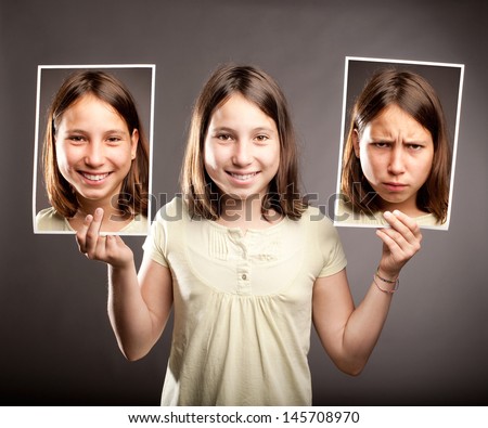 portrait of young girl holding two photos of herself with happy and sad expressions