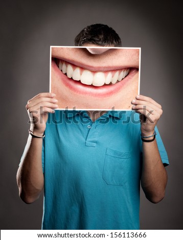 young man holding a picture of a mouth smiling young man holding a picture of a mouth smiling