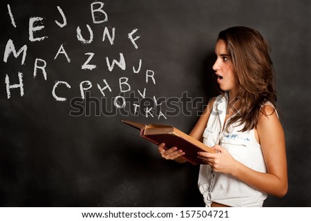 young girl reading a book with letters flying away