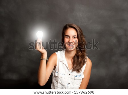 young woman holding a lightbulb in front of chalkboard