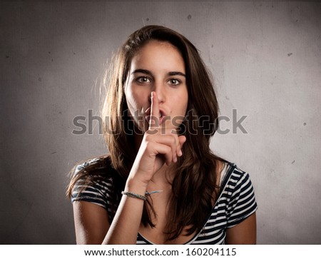 young woman showing silence gesture on a gray background