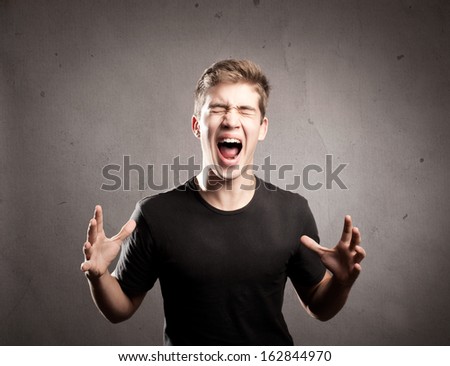 young man screaming on a grey background