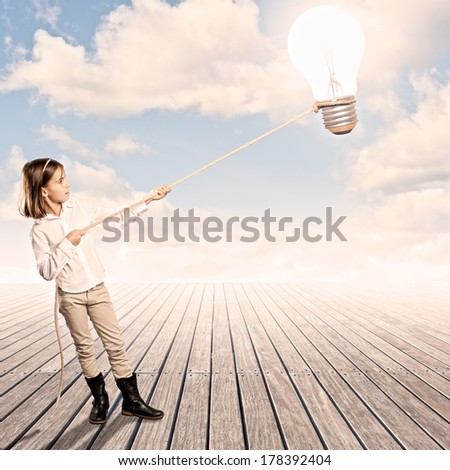 little girl holding a light bulb with a rope on a wharf