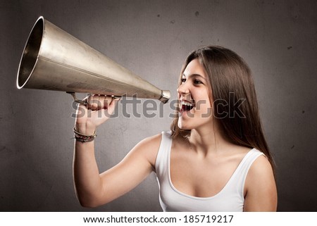 young woman shouting with an old megaphone on a gray background