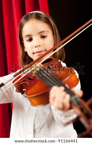 little girl playing violin on stage theater