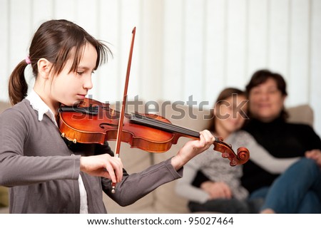 young girl playing violin with her family at home