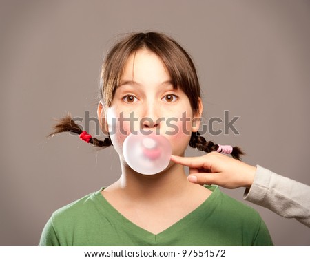 young girl making a bubble from a chewing gum
