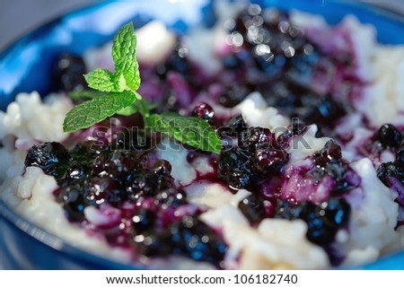 Rice pudding with blueberries in the blue bowl  (Selective Focus, Focus on the front)