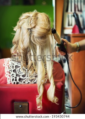 The hairdresser does a hairstyle to the bride