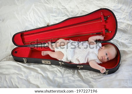 Funny pictures as a little girl lying in the case of a violin