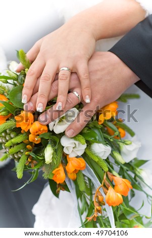 Detail of hands of wedding couple with wedding bouquet