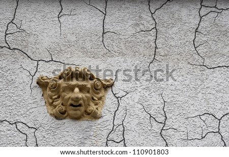 Sculpture of man\'s face on the wall of an old house. Conceptual image about emotions, feelings, depression, frustration, pain,suffering