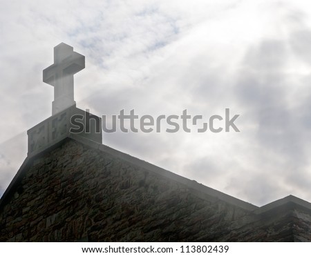 Christian stone cross on the roof and the light from the sky Conceptual image of a Christian spirituality