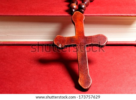 Wooden Christian cross on a red book.