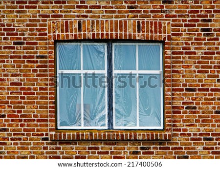 Window under the plastic film in the brick wall