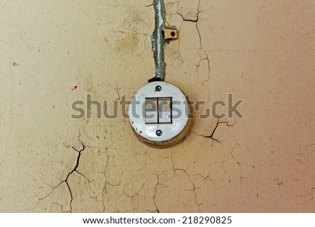 Old electrical switch and cable on a decrepit wall