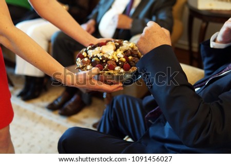 sweets like confectionery and chocolates served by a girl, dressed red, to elder people, a traditional ceremony for ramadan feast of sacrifice feast known as eid al-adha