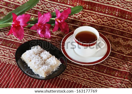 Thai tradition dessert with banana stuff and coconut slices topping and tea cup.